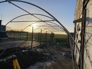 An image of a large polytunnel being erected looking out onto fields.